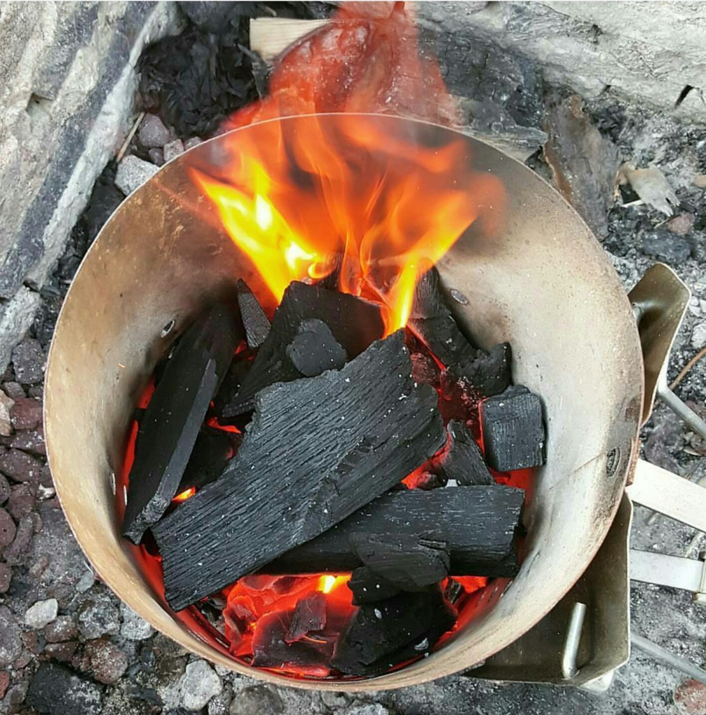 Lighting coals (such as lump charcoal seen here) in a chimney starter is a great way to go.