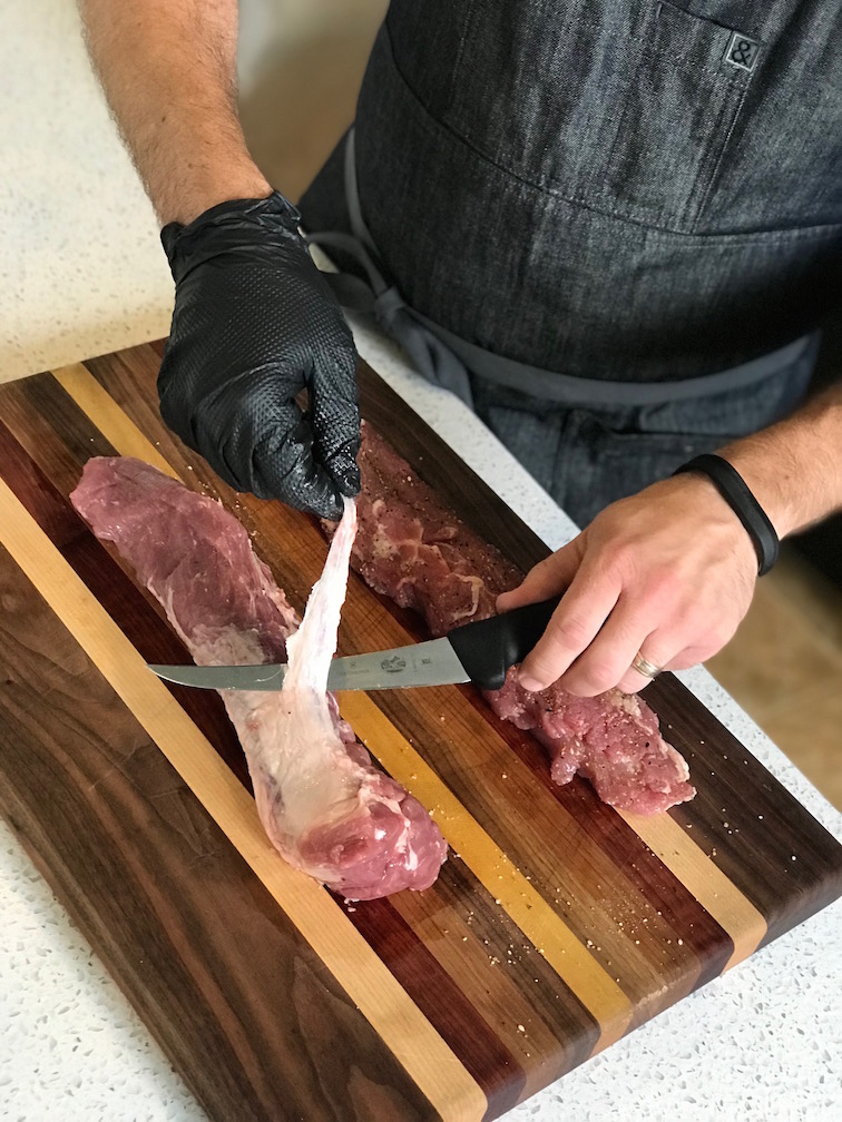 Trimming silver skin from the pork tenderloins.