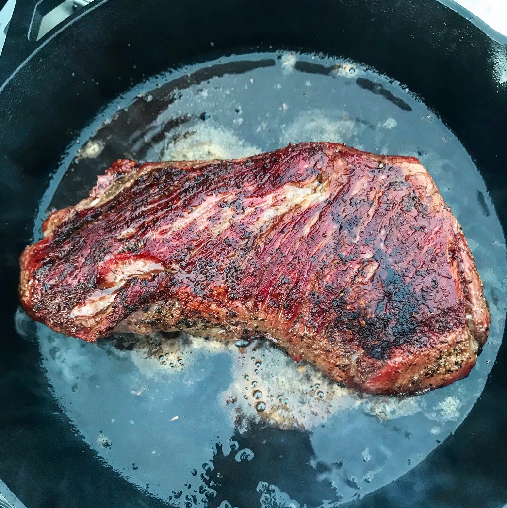 Tri tip getting seared in a cast iron skillet. 