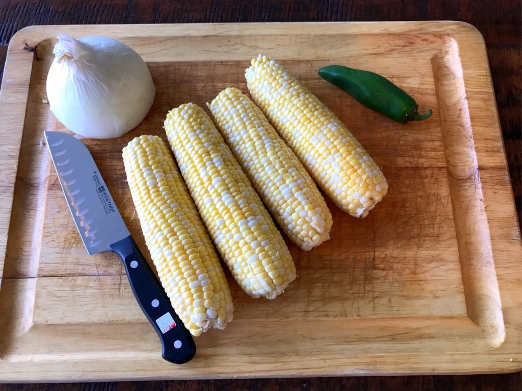 Cutting board with corn, onion, and jalapeno.