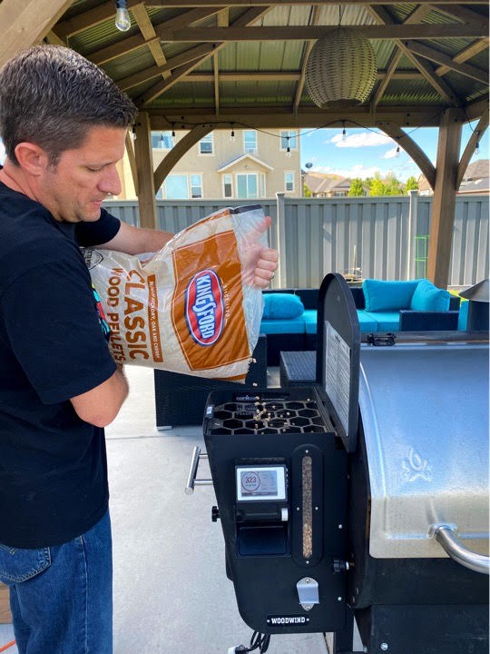 Pouring Kingsford wood pellets into the hopper of my pellet grill. 