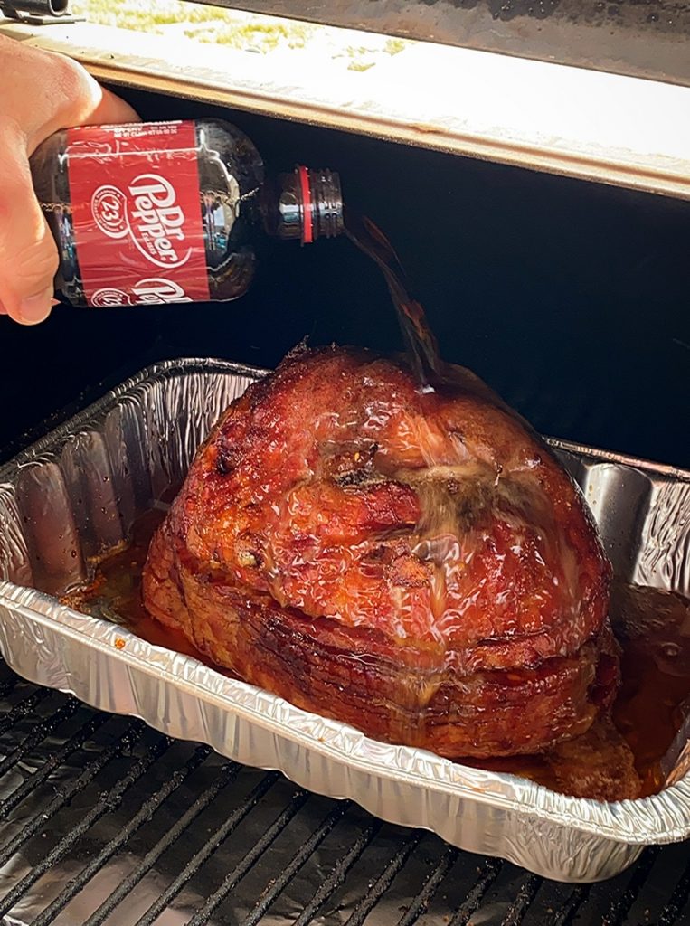Pouring Dr Pepper on a BBQ smoked ham.