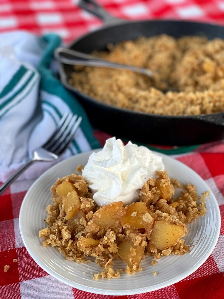 Cast iron apple crisp served up with whipped cream. 