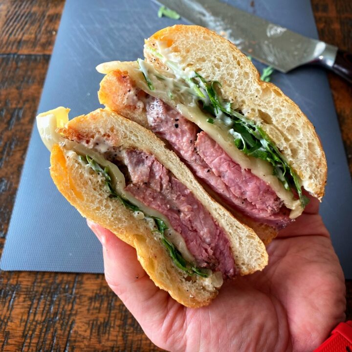 Smoked tri tip sandwich sliced in half.