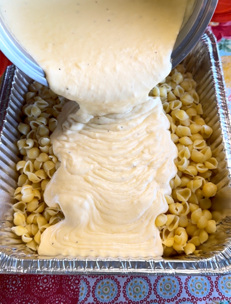 Pouring the cheese sauce over the shells. 