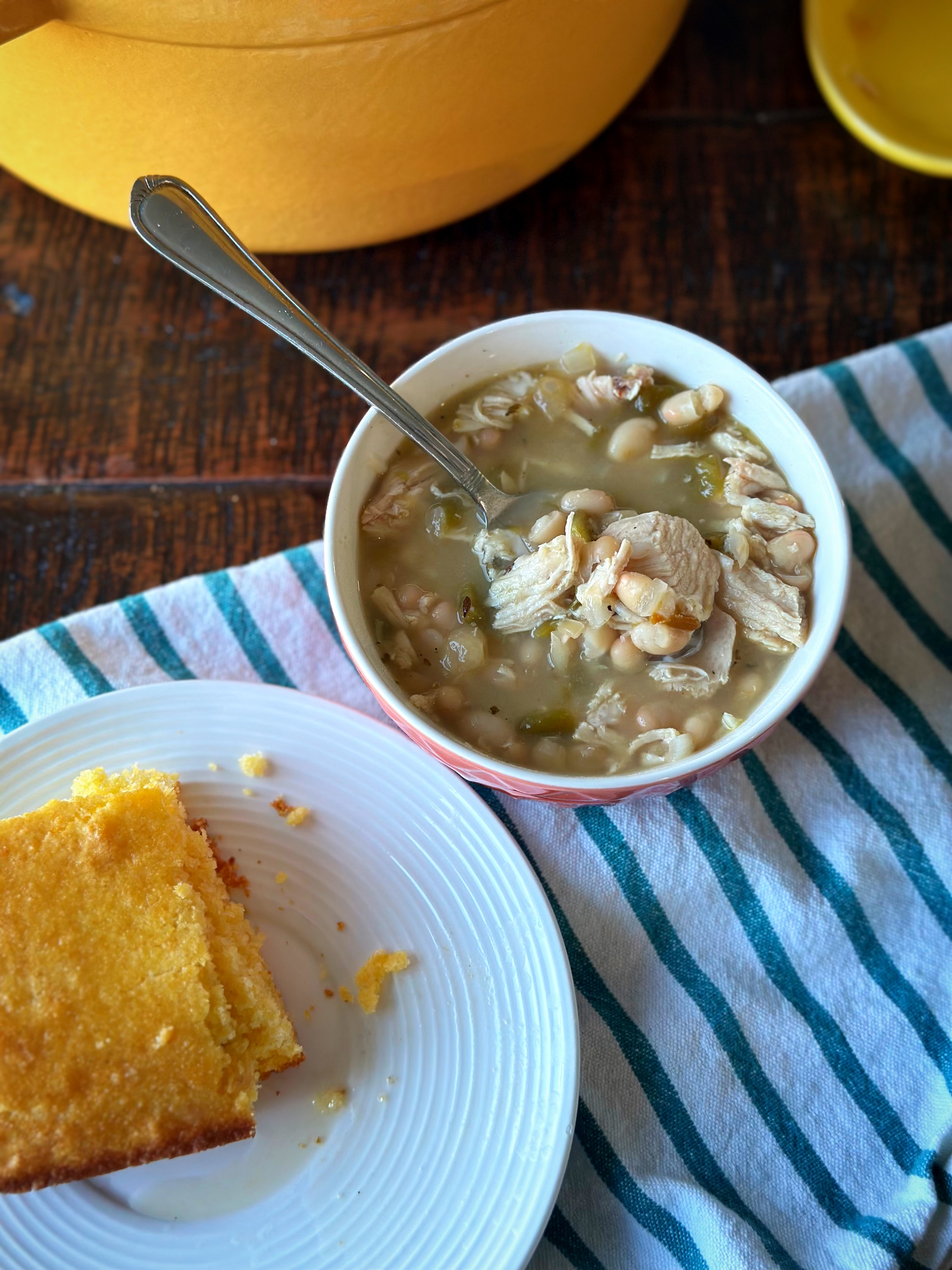 White bean chicken chili in a small bowl with a side of homemade cornbread. 