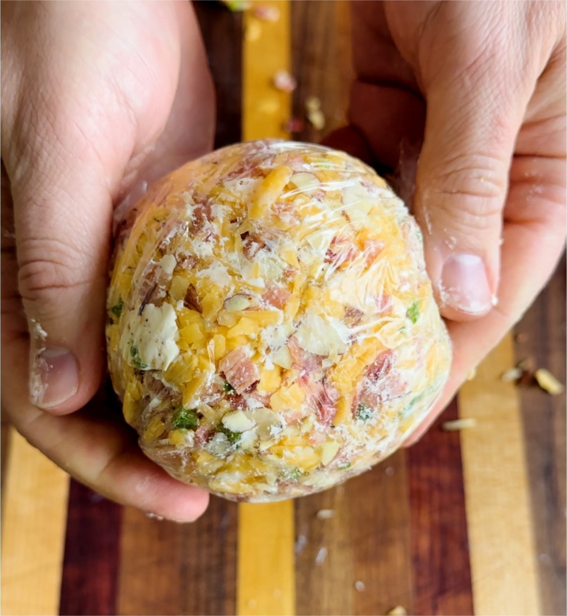 Smoked cheese ball covered in plastic wrap. 