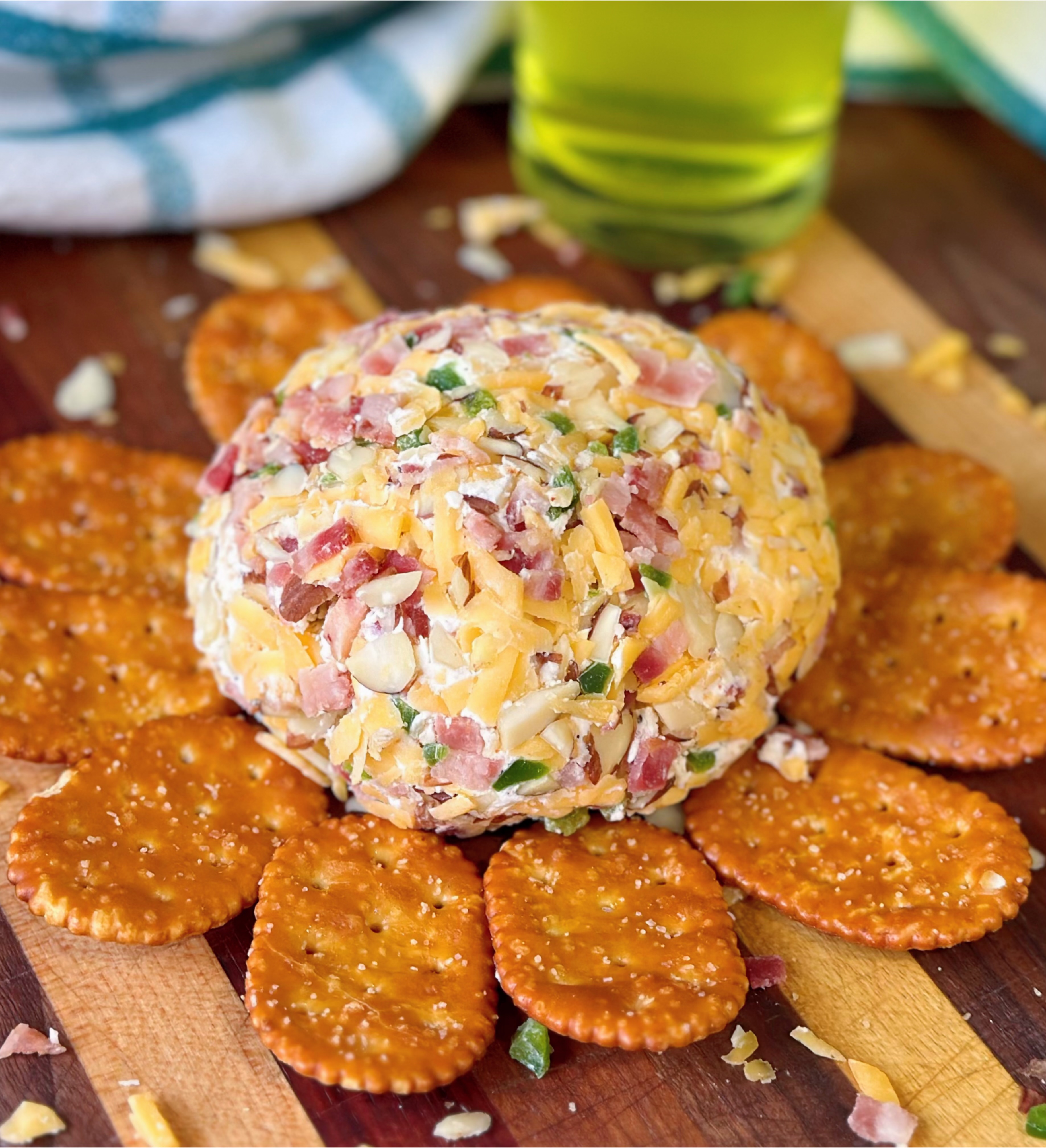 Jalapeño popper cheese ball on a cutting board served with pretzel-style crackers. 