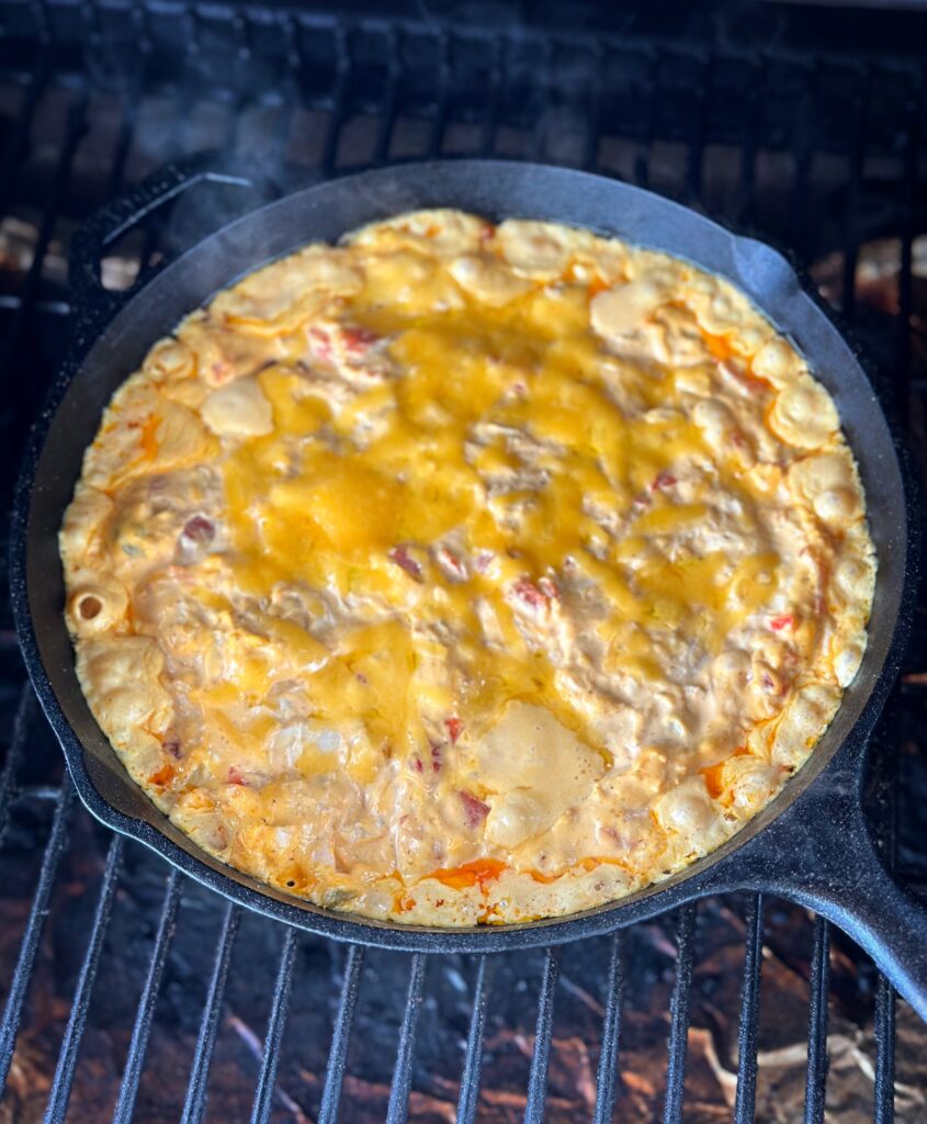 Cast iron skillet full of smoked Buffalo chicken dip on the grill. 