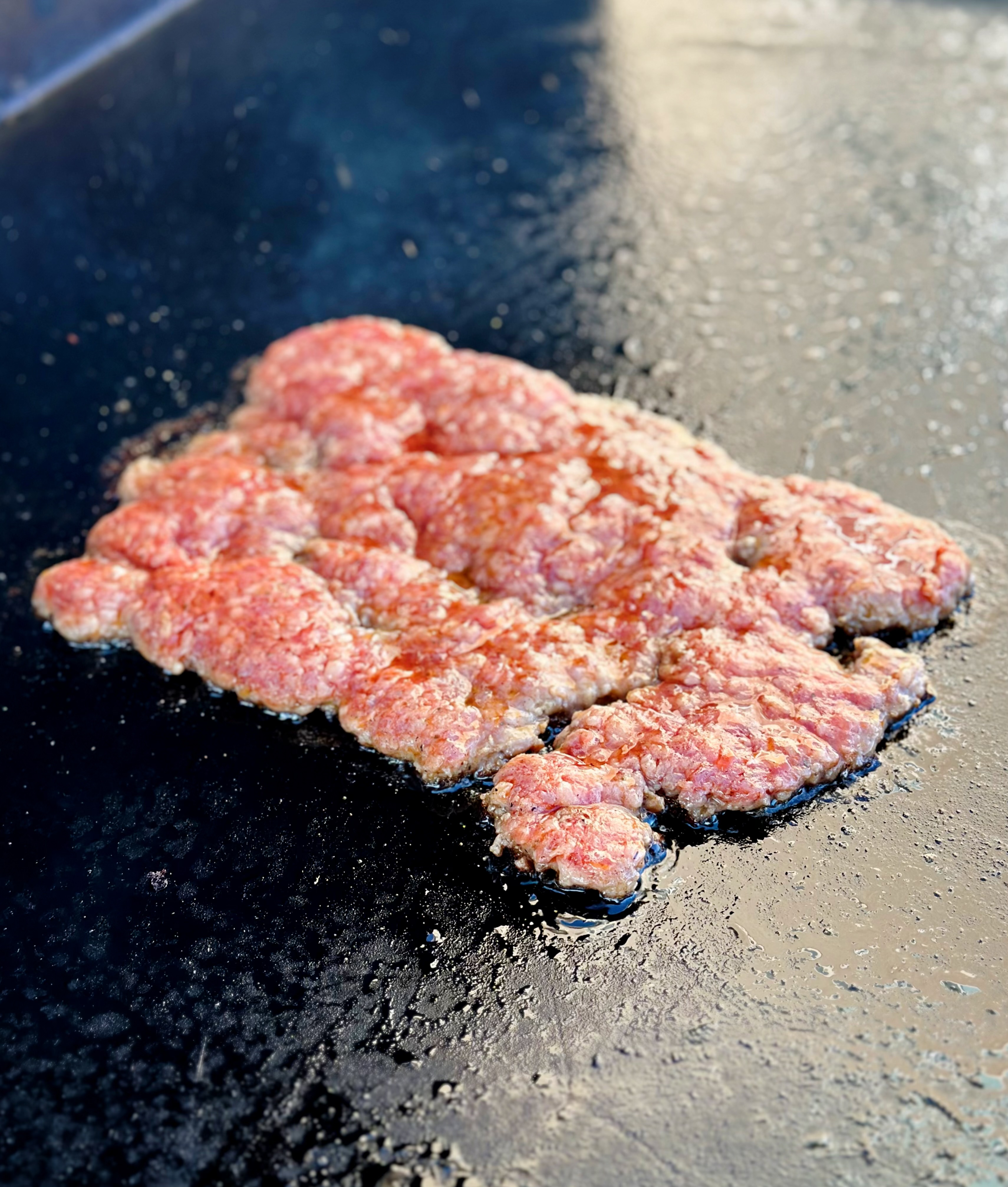 Ground sausage being cooked on the griddle. 